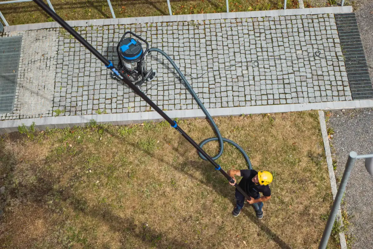 Mies käyttää imuria ja teleskooppiputkea